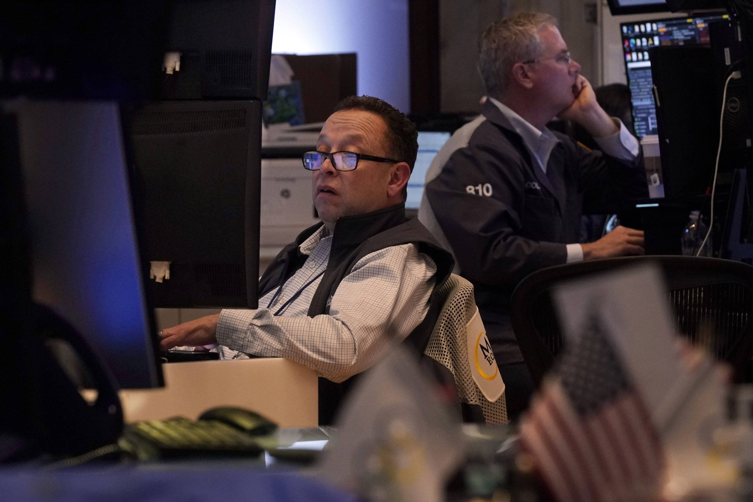 A pair of traders work on the floor of the...